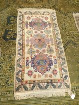 A border pattern and fringed rug with three central guls and stylised leaf border,