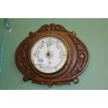 A carved oak Aneroid Barometer, 11" wide x 9" high.