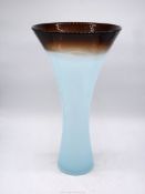 A tall glass trumpet Vase in light blue merging with brown rim and having a thick clear base with