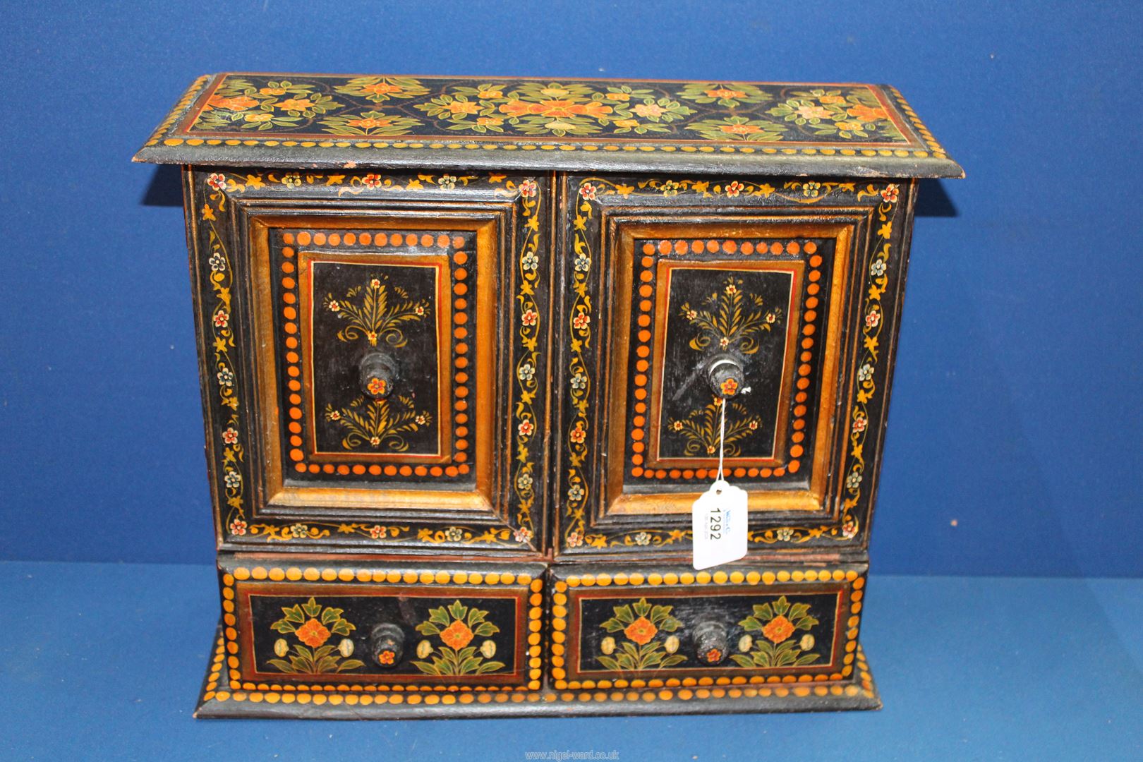 A black cabinet having painted floral decoration with two doors and two drawers,