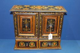 A black cabinet having painted floral decoration with two doors and two drawers,