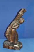 A heavy cast Bronze figure of a female peasant carrying firewood on her back, signed T.