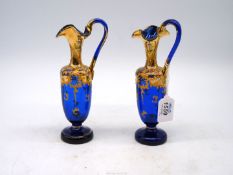 A pair of 19th century blue glass decorative Ewers with gilt and painted overlay, 8" tall.