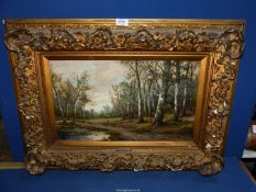 An ornately framed Oil on canvas depicting a woodland scene with trees lining a path past a pond