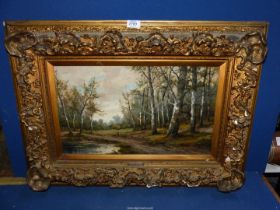 An ornately framed Oil on canvas depicting a woodland scene with trees lining a path past a pond