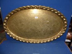 A large Brass oval Tray having thumb print edge and foliage design. 36" x 22".