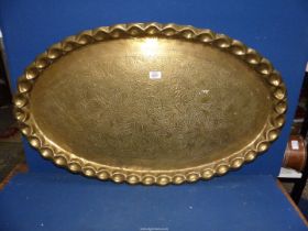 A large Brass oval Tray having thumb print edge and foliage design. 36" x 22".