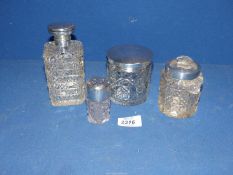 Four glass dressing table pots, three with silver tops,
