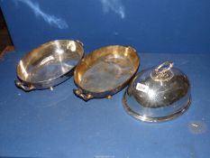 Two plated serving dishes on button feet and a food cover.