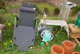 A work bench stand, hose & reel and a lounger.