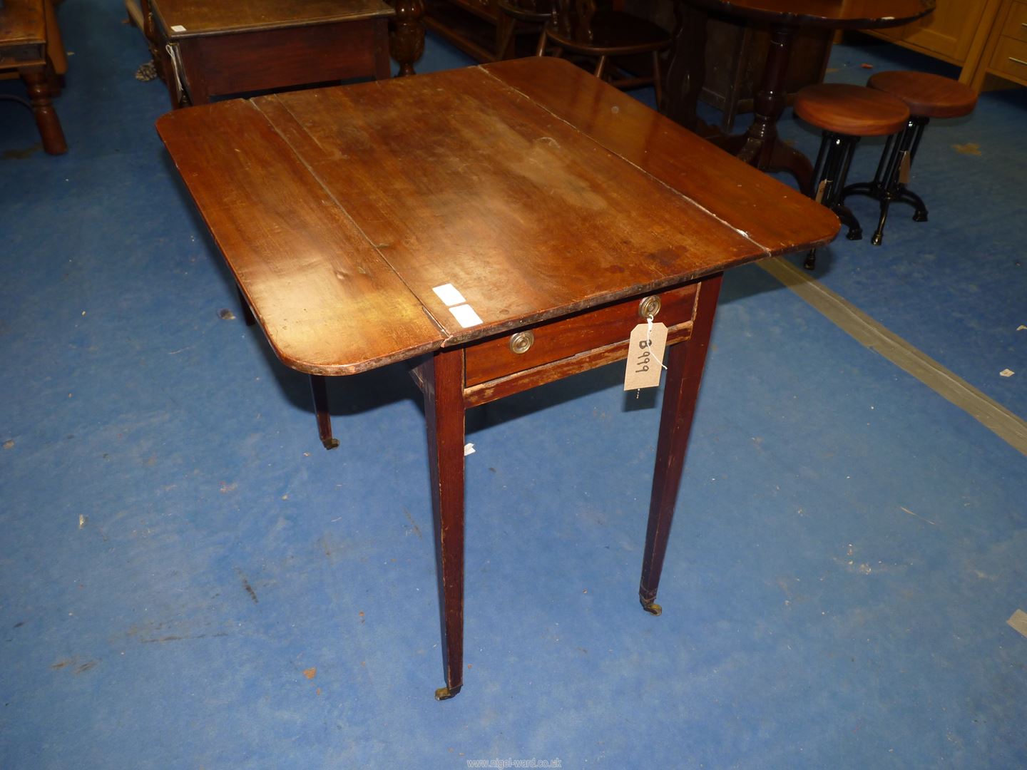 A Mahogany Pembroke table, standing on tapering square legs with brass castors, with drawer,