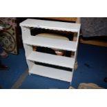 A white painted wall shelf unit having four scalloped edge shelves.