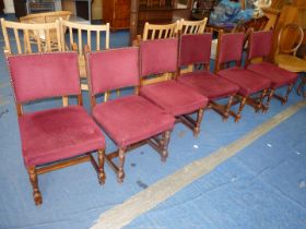 A set of six burgundy red upholstered dining chairs.