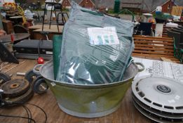 A galvanized bath and a tarpaulin and wheelbarrow flat pack.