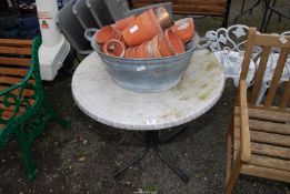 A galvanized bath with china clay pots and a circular table.