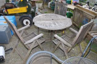 A circular teak patio table, 43" wide x 29" high and three folding chairs.