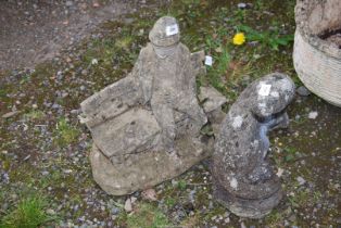 A concrete figure of a man sat on a garden bench, plus an otter.