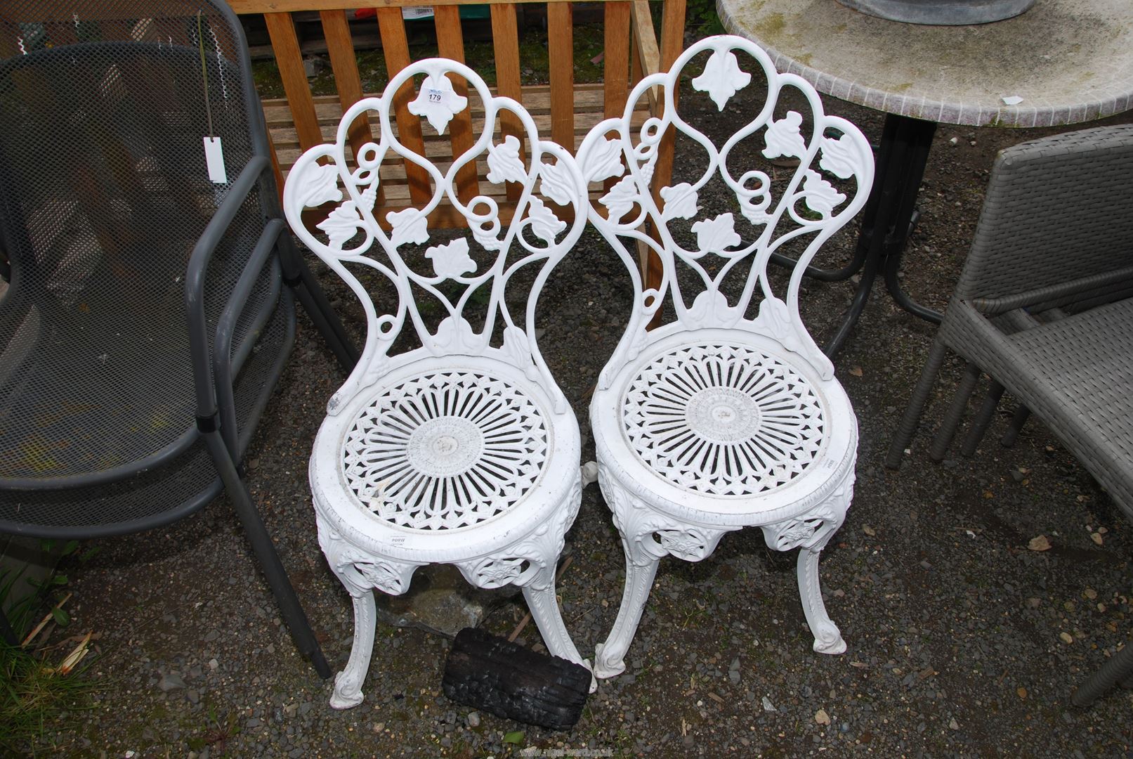 A pair of aluminium chairs with leaf detail.
