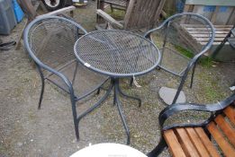 A small circular patio table with two chairs.