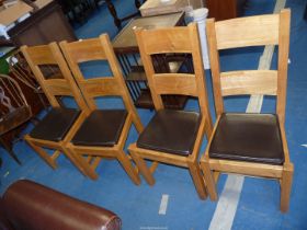 A set of four brown faux leather dining chairs with ladder backs.