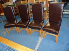 A set of 4 brown faux leather dining chairs.