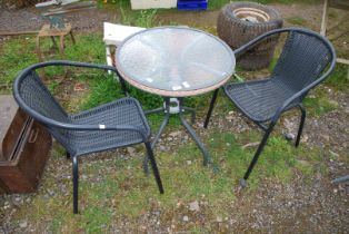 A small glass topped patio table, 23 1/2" wide x 28" high with two chairs.
