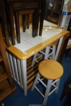 A tiled top Kitchen Table and pair of circular stools, 35 1/4'' x 23 1/4'' x 34'' high.