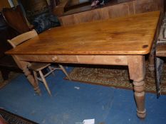 A large Pine scrubbed top Kitchen Table standing on turned legs and having a drawer to one side