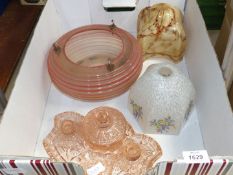 Three glass lamp shades and a pink glass dressing table set.