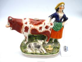 A Staffordshire flatback/cow creamer in ochre decoration with calf at her feet and milkmaid in