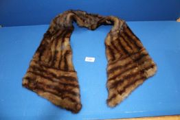 A fur scarf with brown lining slot for securing.