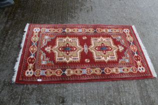 A bordered, patterned and fringed Rug, burgundy ground with green,