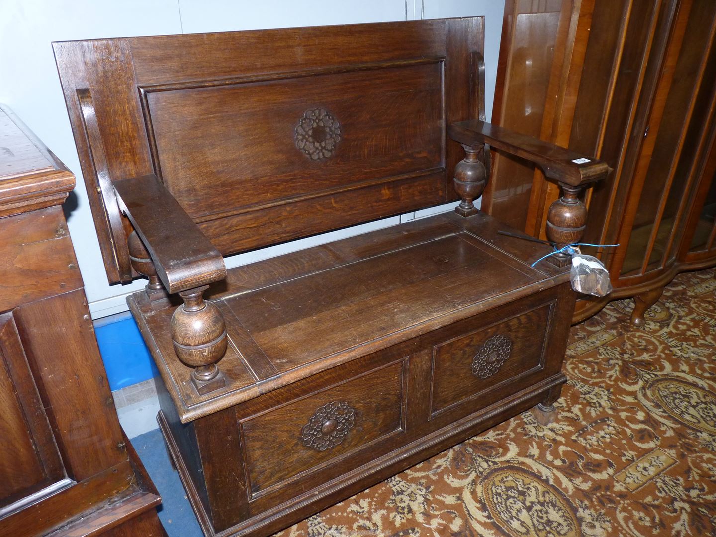 An Oak Monks Seat having a locker base, the arms supported on bulbous turned supports,