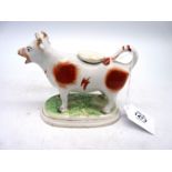 An early 19th century cow creamer in over glazed red ochre on bocage base, 6 1/2" x 5" tall.