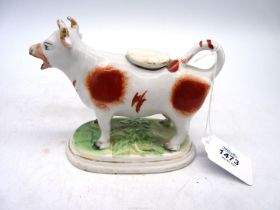 An early 19th century cow creamer in over glazed red ochre on bocage base, 6 1/2" x 5" tall.