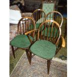 A set of four solid wood seated Ercol Dining Chairs having stick backs and green upholstered pad