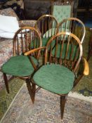 A set of four solid wood seated Ercol Dining Chairs having stick backs and green upholstered pad