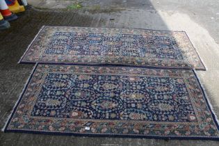 A dark blue ground rug 89" x 38" and matching blue ground rug with pink and cream motifs, 74" x 36".