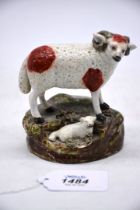 A Staffordshire figure of a curly horned ewe with a lamb at her feet, 4 1/4" x 4 1/4" tall.