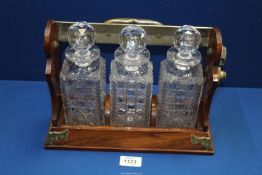 A Betjeman's Tantalus with three cut glass decanters (one rim chipped).