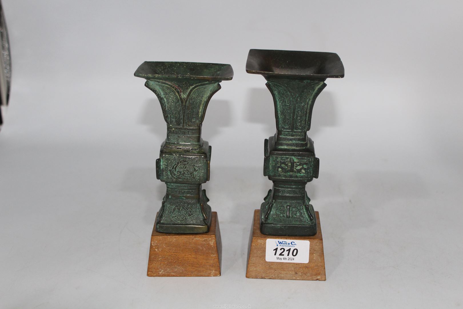 A pair of small Chinese bronze 'Gu' vases, probably Ming dynasty, on custom made wooden stands,