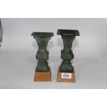 A pair of small Chinese bronze 'Gu' vases, probably Ming dynasty, on custom made wooden stands,