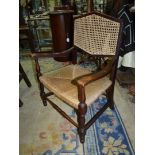 A Mahogany framed low open armed Elbow Chair standing on turned front legs and having a woven