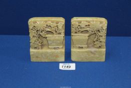 A pair of Soapstone Bookends having carvings of flowers tumbling from a vase, 3 1/4" x 4 1/4".