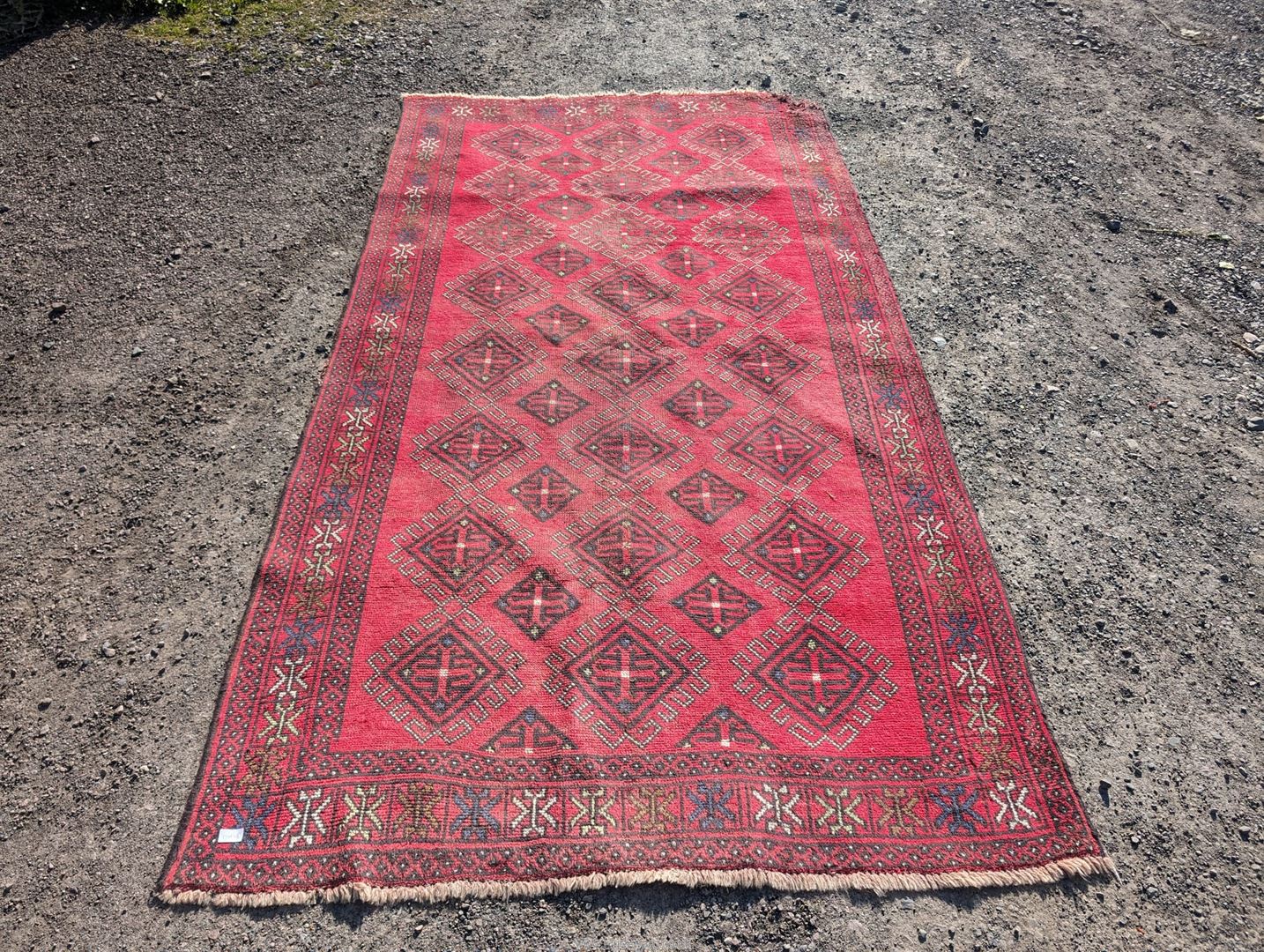 A large border patterned rug on a red ground having black central diamonds,