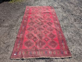 A large border patterned rug on a red ground having black central diamonds,