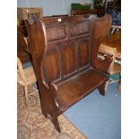 A peg-joyned Oak Settle having a pair of carved panels to the backrest with arch and stylised