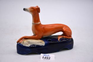 A Staffordshire seated hound spill vase on blue base with rabbit at its feet, 7" x 5 1/4" tall.
