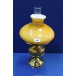 An Oil lamp having brass base with clear chimney and mustard colour glass shade, 19" tall.