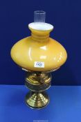 An Oil lamp having brass base with clear chimney and mustard colour glass shade, 19" tall.